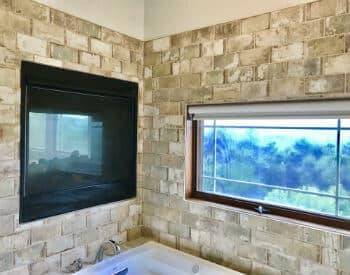 All stone bricks wall above soaking tub with a window with a view of the mountains, also a built in all season fireplace